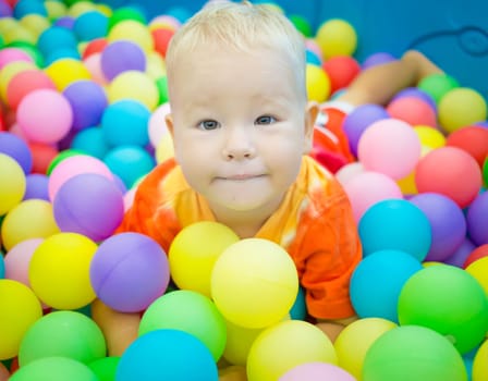 Cute kid boy playing with colorful balls