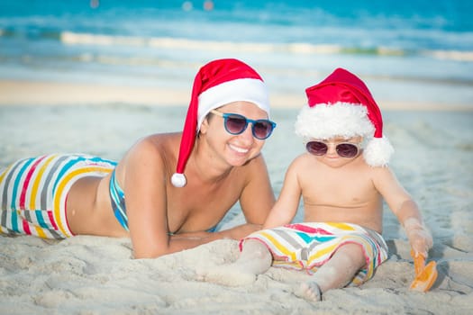 Baby and mother on the beach. Christmas concept