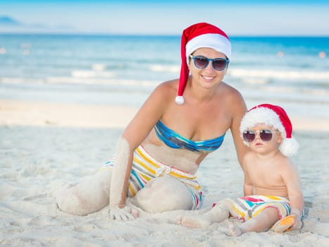 Baby and mother on the beach. Christmas concept