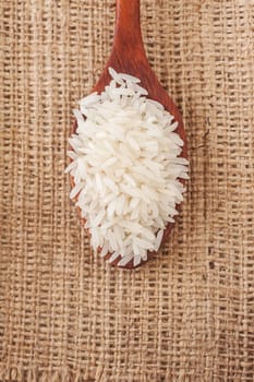 Rice, White rice in wooden spoon on a hemp sack background, Selective focus