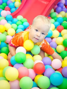 Cute kid boy playing with colorful balls