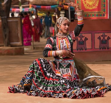 Beautiful Kalbelia dancer in ornate black costume trimmed with beads and sequins at the Sarujkund Fair near Delhi in India.
