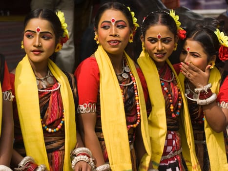 Group of teenage Indian dancers in traditional tribal outfit spot something of interest at the annual Sarujkund Craft Fair in Haryana near Delhi, India.
