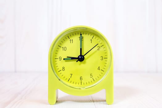 Green alarm clock on the wood background