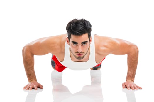 Athletic young man making push-up, isolated over a white background