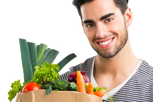 Handsome young man carrying a bag full of vegetables, isolated over white background