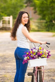 A beautiful young woman with her bicycle smelling wildflowers