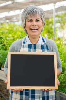 Beautiful mature woman gardening and looking at camera while smiling