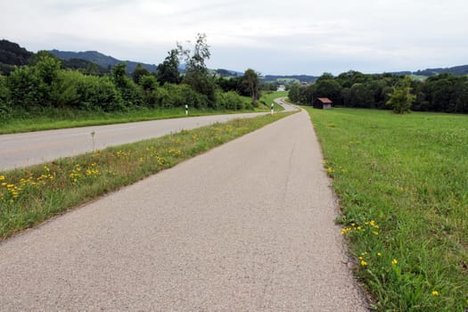 A country road with a bicycle path and footpath