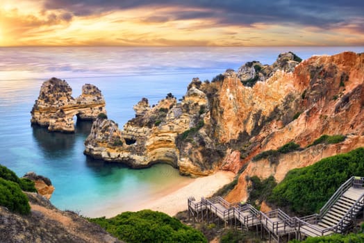 The beautiful Camilo Beach in Lagos,Portugal,with its magnificent cliffs and the blue ocean colorfully lit at sunrise