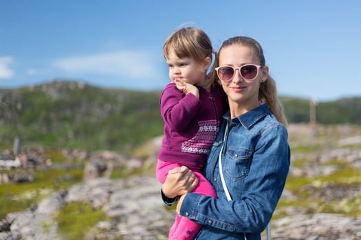Young mother in sunglasses with her daughter at the hands of nature.
