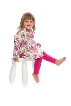 Little smiling girl sitting on a chair in the studio, isolate on white background.