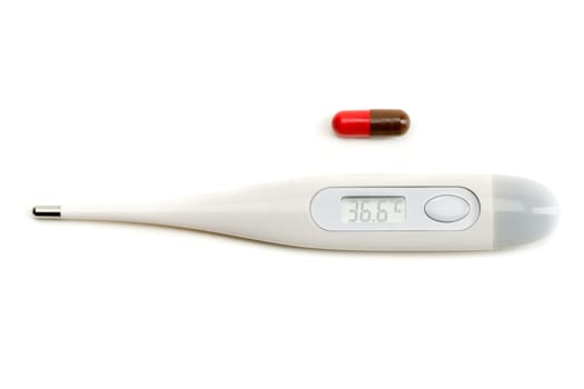Electronic thermometer and pill on white isolate.