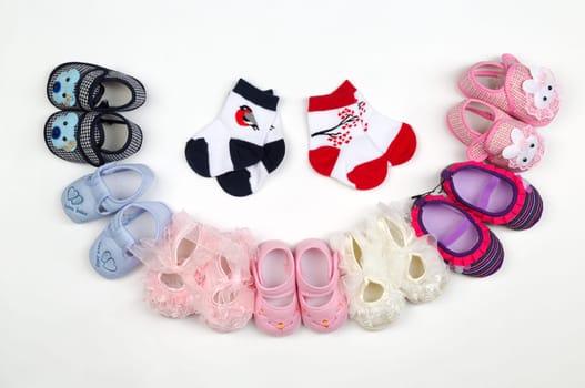 Children's shoes and socks laid semicircle on a light background.