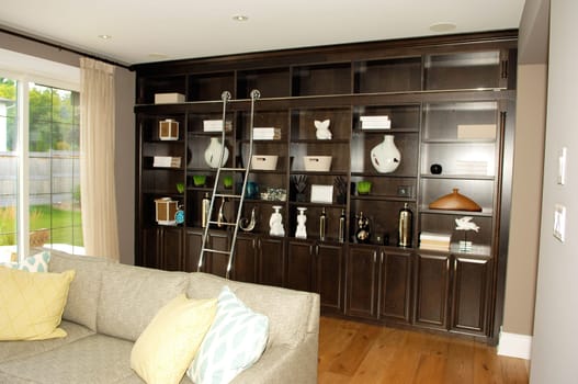 The living room in a new house with a sofa and a shelf over the whole.wall and a ladder..