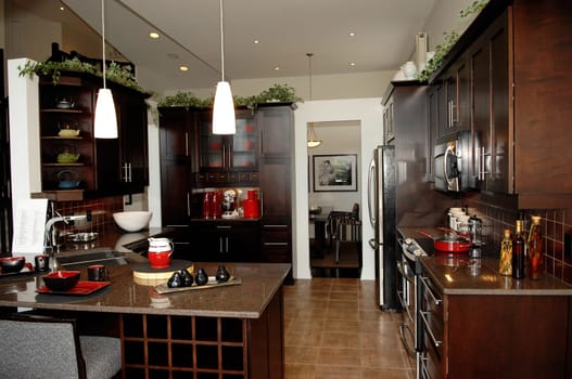 A big spacious kitchen in a new house with appliances and a breakfast.counter in dark brown wood..