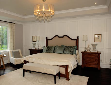 A big elegant bedroom in a new house with a window and great light fixture.in pastel color..