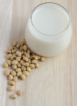 Fresh Soy milk (Soya milk) and dried soybean seeds on wooden background. Traditional staple of East Asian cuisine
