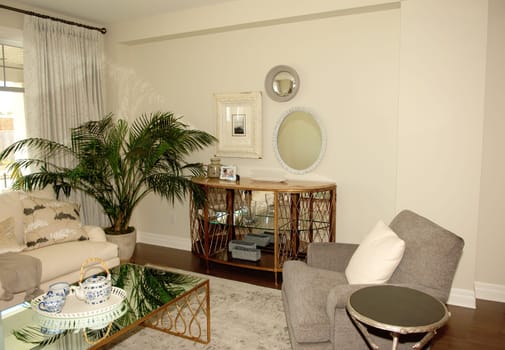 A lovely living room in a new house with a table, chairs and a big palm,.furnished and a window..