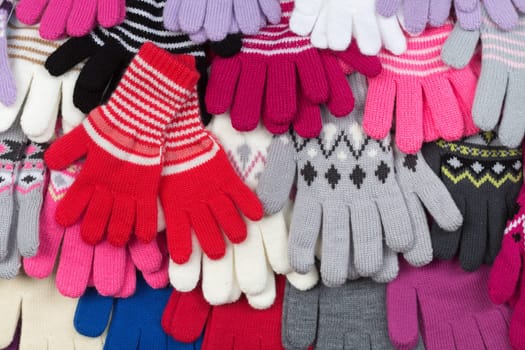Colored knitted gloves stacked background.