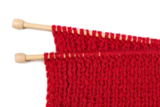 Red knitted wool fabric on wooden spokes. Isolate on white.