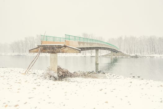 Landscape of an angled view of a flood damaged bridge in winter.