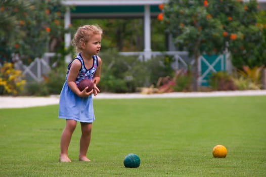 little girl plays with a ball a ball on a meadow