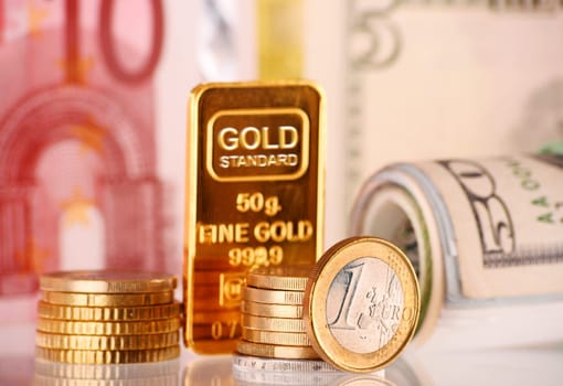 Composition with 50 gram gold bar, banknotes and coins.