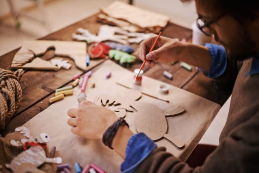 Craftsman with paintbrush painting paper deer before Christmas
