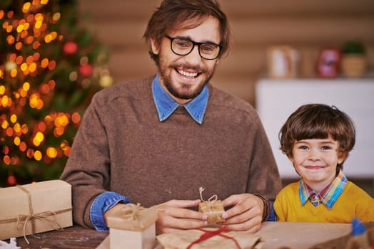 Happy young man and his son with wrapped gifts looking at camera and smiling