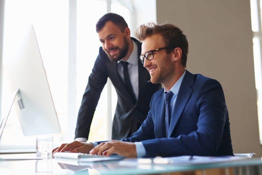 Two businessmen working with computer in office