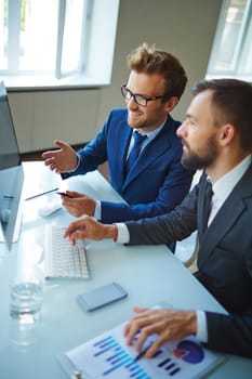 Modern businessmen discussing data in front of computer in office