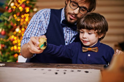 Handsome man and little boy printing Christmas tree on paper