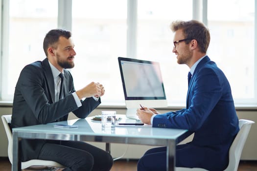 Confident businessmen sitting by table during consultation
