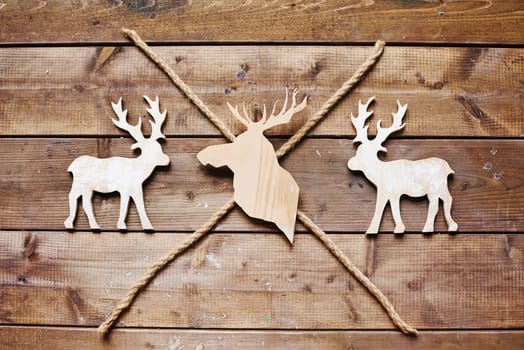 Three reindeers and two ropes on wooden background
