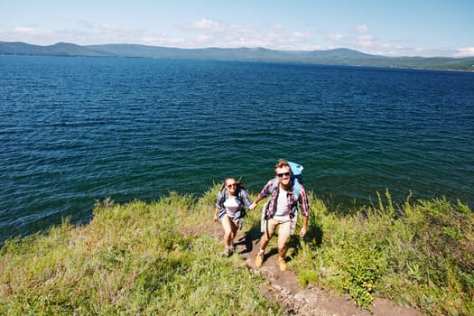 Happy young travelers hiking by the seaside