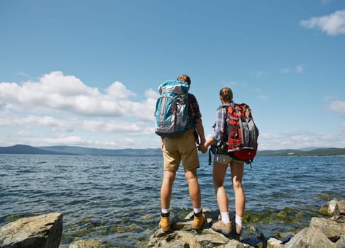 Rear view of affectionate hikers admiring sea