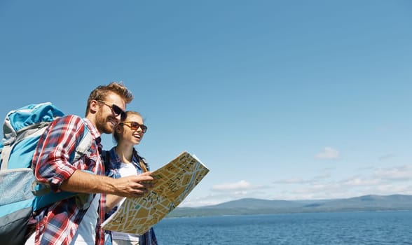 Happy hikers in sunglasses looking in guide on background of the sea