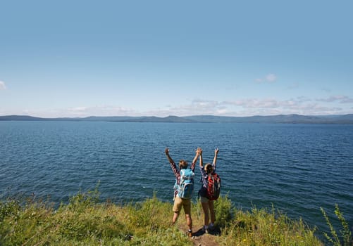 Ecstatic hikers with raised arms standing by the sea