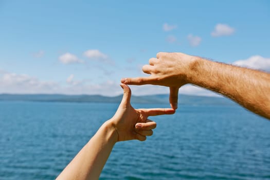 Human hands making frame against sea and skyline