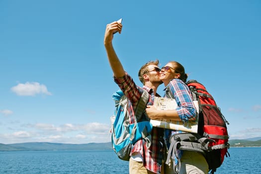 Handsome man making selfie during trip while kissing his girlfriend
