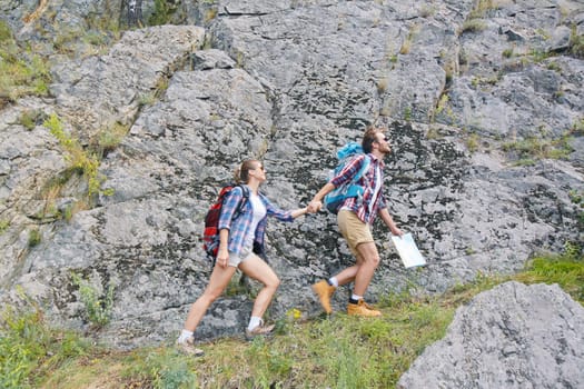 Young hikers holding by hands while walking along rock