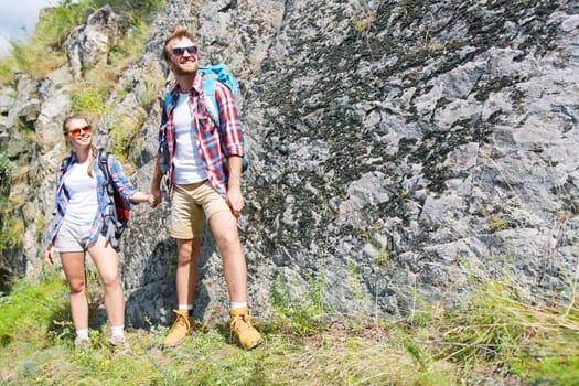 Happy hikers holding by hands while standing by rock