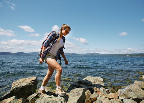Pretty hiker walking on rocks by the seaside