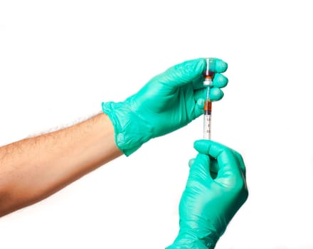Hands of the doctors with green gloves filling a syringe