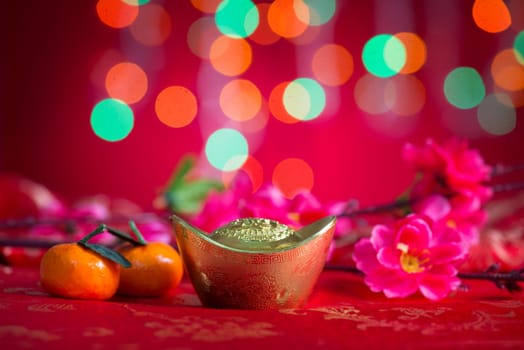 Chinese new year decorations, gold ingot on red glitter background.