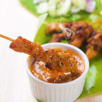 Delicious chicken sate or satay, skewered and grilled meat, served with peanut sauce. Fresh cooked with steamed and smoke. Hot and spicy Asian dish.