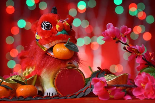 Chinese new year festival decorations, miniature dancing lion and mandarin orange, on glitter red background.