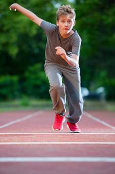 Frontal full-body view of a young male teenager on a tartan track towards the camera