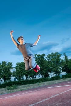 Full-body view of a young male teenager during an aerial jump on the sports field